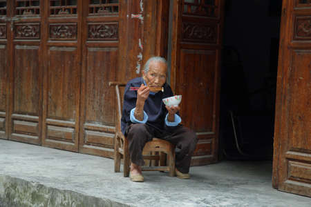 FURONG, CHINA - SEPTEMBER 14, 2015: local old man eating in tourist and charming ancient Furong (hibiscus) village, Hunan province, China.のeditorial素材