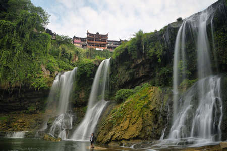 FURONG, CHINA - SEPTEMBER 15, 2015: Man fishing in front of the waterfall in Furong (Hibiscus) ancient village, Hunan province, China.のeditorial素材