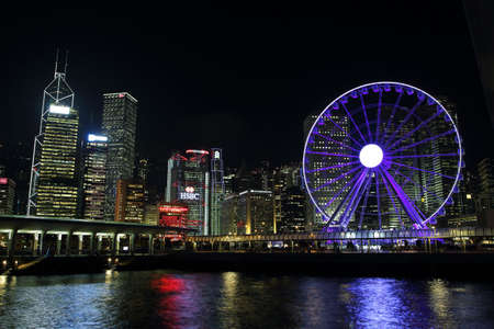 HONG KONG, CHINA - SEPTEMBER 24, 2015: Ferris wheel and skyscrapers illuminated in Victoria Harbour, Hong kong islandのeditorial素材