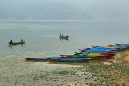 KATHMANDU, NEPAL - APRIL 10 2016: Colorful boats and people enjoying of beautiful sunset at Fewa lake in Pokhara, Nepalのeditorial素材
