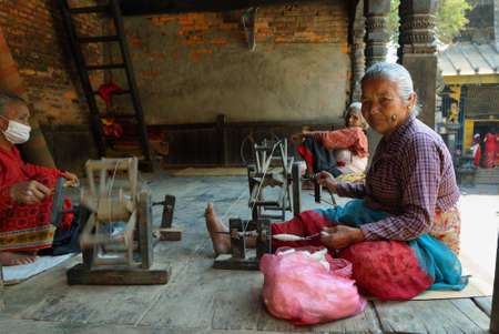 BHAKTAPUR, NEPAL - APRIL 20, 2016: hindu old women weaving in the street of medieval town of Bhaktapur in Nepal.のeditorial素材
