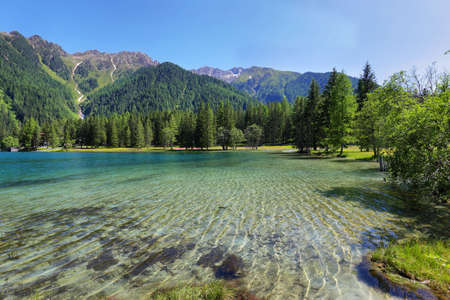 Anterselva Lake surrounded by red and yellow flowers in summer, Trentino Alto Adige, Italy