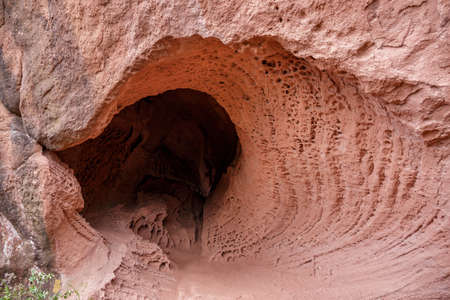 Cave with holes in stone in Areny mountain - Tafoni weathering in red sandstone. Tarragona, Spain