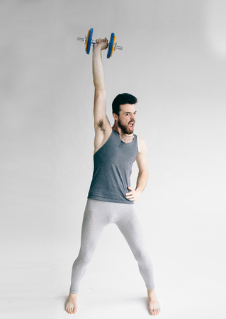 Guy lifting one dumbbell. young student training to become strongerの写真素材