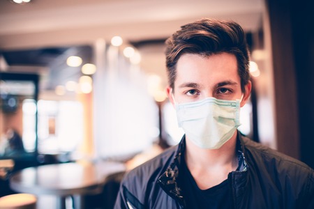 Man wearing medical face mask in the a restaurant. Male wearing face mask, protection from virus infection.の写真素材