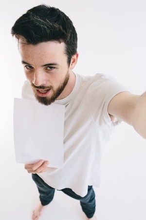 Bearded man holding a blank white sheet of paperの写真素材