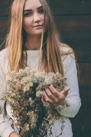 pretty young blond woman holds bouquet of dried flowersの写真素材
