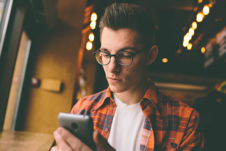 Close up on the hands of a young handsome man using  smartphone, tapping the screen - technology, social network, communication conceptの写真素材
