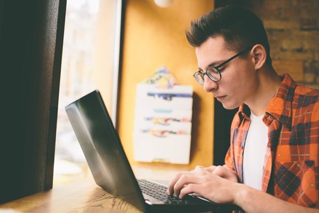 Happy casual man using laptop computer in cafe.の写真素材