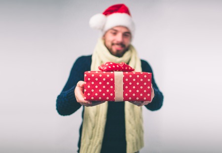 Handsome man in a Christmas hat holding gifts on white backgroundの写真素材