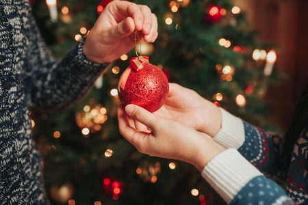 Merry Christmas and Happy New Year . Young couple celebrating holiday at home. Man and woman holding a Christmas ballの写真素材