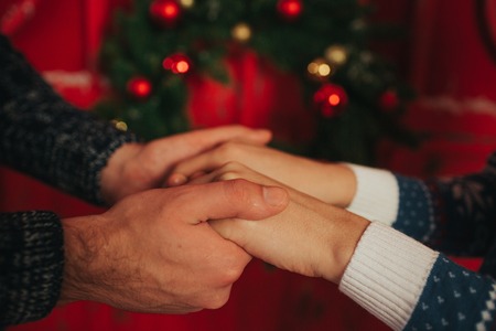 Merry Christmas and Happy New Year . Young couple celebrating holiday at home. Happy young man and woman hug and give each other giftsの写真素材