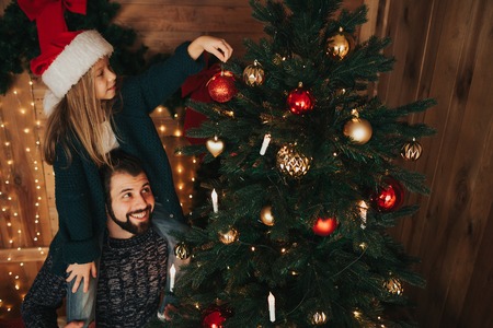 Happy father and his little daughter decorating the Christmas tree at home.の写真素材