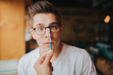 Surprised Teenage couple holding pregnancy test. Woman Show Man Positive Pregnancy Test Conflict...
