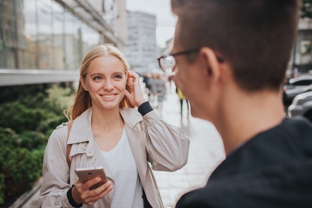 ouple or friends laughing funny and having fun with a smart phone in a big city streetの写真素材