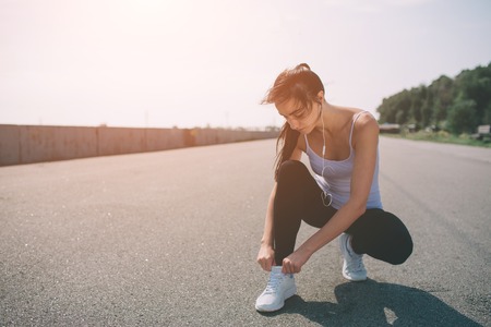 Beautiful woman running during sunset. Young fitness model near seaside. Dressed in sportswear. Cords sneakers.の写真素材