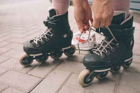 Pretty brunette girl posing with roller skates outdoors. Summer lifestyle portraitの写真素材