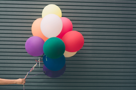 Multicolored, latex balloons filled with helium near the gray wall. , festive concept with a place for your textの写真素材