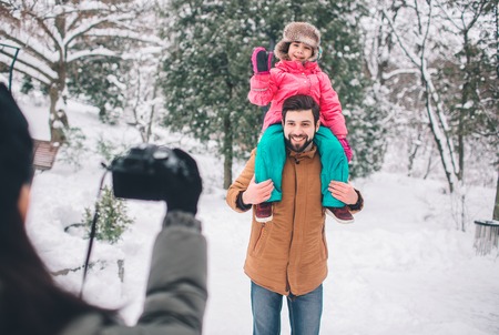 arenthood, fashion, season and people concept - happy family with child in winter clothes outdoors....