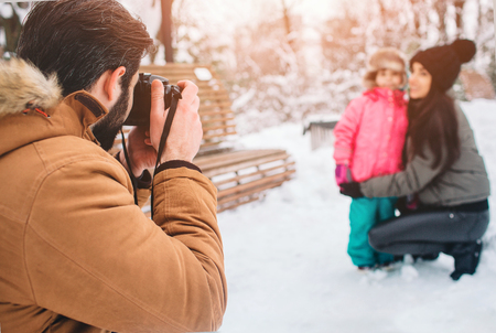 arenthood, fashion, season and people concept - happy family with child in winter clothes outdoors. Take photos with each otherの写真素材