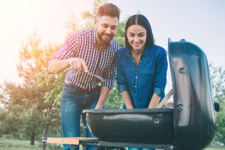 Friends making barbecue and having lunch in the nature. Couple having fun while eating and drinking at a pic-nic - Happy people at bbq party.の写真素材