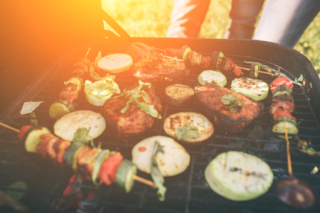 Friends making barbecue and having lunch in the nature. Couple having fun while eating and drinking at a pic-nic - Happy people at bbq party.の写真素材