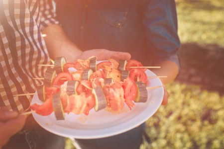 Friends making barbecue and having lunch in the nature. Couple having fun while eating and drinking...