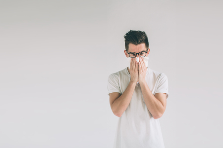 studio picture from a young man with handkerchief. Sick guy isolated has runny nose.の写真素材