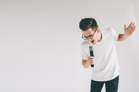 Boy Rocking Out. Image of a handsome man singing to the microphone, isolated on light.の写真素材