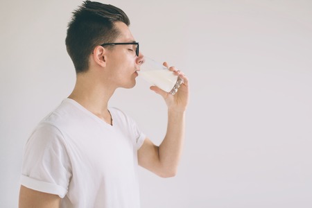 man is drinking fresh glass of milk isoladed on white backgroundの写真素材