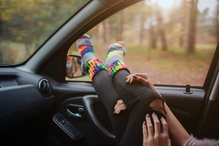 Autumn, Auto travel. Cose-up of a woman during the road trip in a car. Woman feet in warm socks on car dashboard.の写真素材
