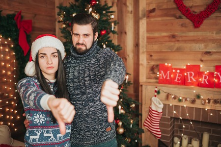 Merry Christmas and Happy New Year . Young couple celebrating holiday at home. Thumb down, new year, coupleの写真素材