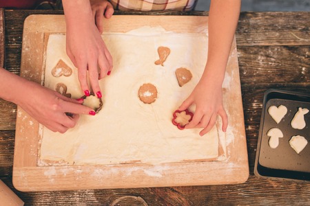 Cooking homemade cakes. Happy loving family are preparing bakery together. Mother and child daughter girl are cooking cookies and having fun in the kitchen. Roll the dough. Molds from dough.の写真素材