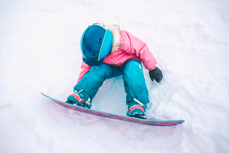 Snowboard Winter Sport. Little kid girl playing with snow wearing warm winter clothes. Winter backgroundの写真素材