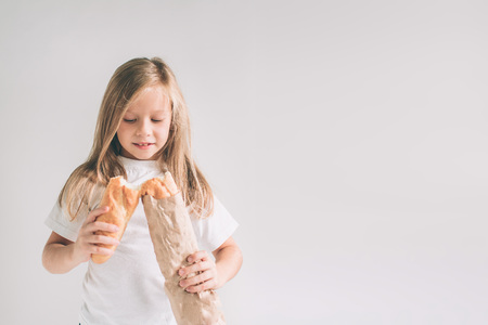 Girl with Bread in hand. Freshly baked bread in the hands. . Child is holding a lot of bread in hands isolated on white background.の写真素材