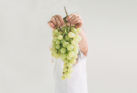 Girl holding grape, close up. concept. isolated on white. Nerd is wearing glasses. Child isolated on white background.の写真素材