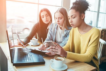 Close up and cut view of three girls sitting together and studying the diagram of money income.