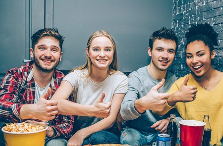 Close up of four best friends sitting together in a small room and posing to camera.の写真素材