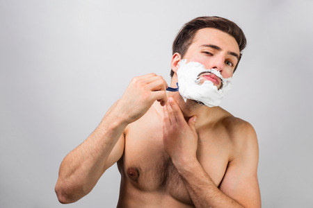 Handsome and attractive man is in the process af shaving his beard.の写真素材