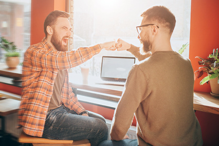 Happy and emotional men are sitting together and screaming. They has put their fists together. The picture is positively emotional. Close up.の写真素材
