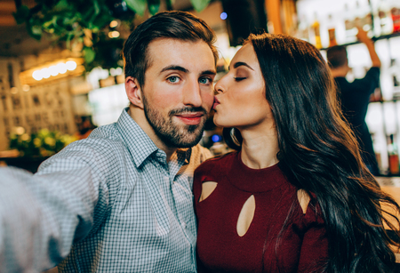 Another selfie of couple. Girl is kissing her partner while he is taking a picture. They look happy together.の写真素材