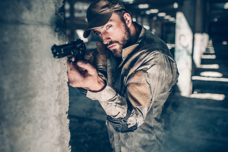 Concentrated and serious man is looking through lens straight forward. He is taking aim. Warrior is waiting. He is not in a rush.の写真素材