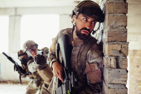Serious and careful man is leaning to wall. He is aiting. There are his partners behind him. Guys are waiting fot the perfect time to attack enemy.の写真素材
