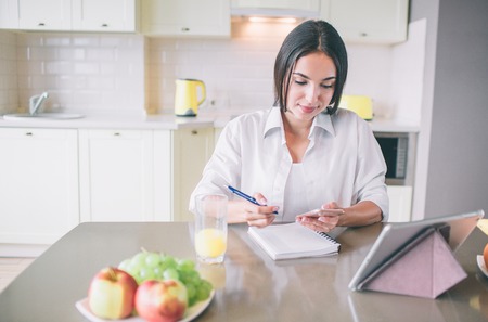 Calm and busy girl sits at table and works.の写真素材