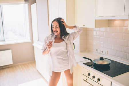 Funny and crazy girl is screaming and dancing in kitchen.の写真素材
