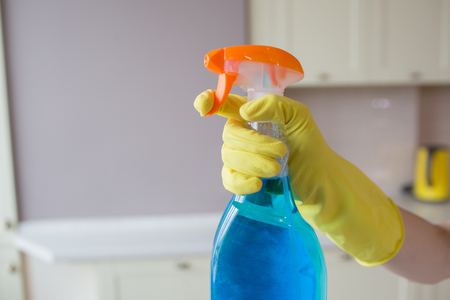 A picture of hand in yellow glove holding spray bottle with blue liquid.の写真素材