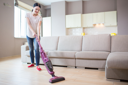 A picture of woman stands in studio apartment and cleaning the floor.の写真素材