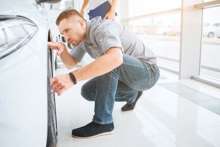 Man checking car in showroom.