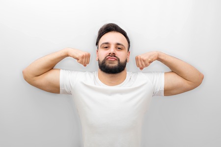 Well-built and strong young man stands and poses on camera. He has good figure and muscles. Isolated on white background.の写真素材