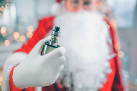 Close up of Santa Claus stands and holds vape in hand. He shows it on camera.の写真素材